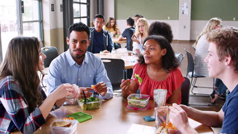 Teacher-And-Students-Eating-Lunch-In-High-School-Cafeteria-During-Recess