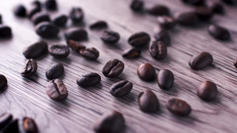Coffee-beans-on-a-wooden-surface-being-swiped-away-by-a-hand