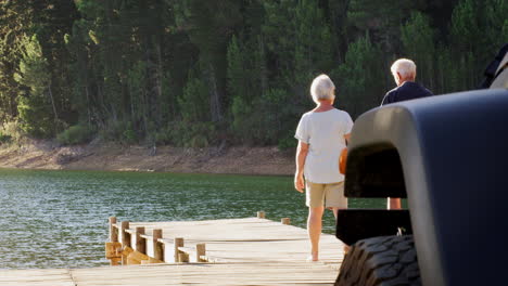 Senior-white-couple-walk-along-jetty-to-admire-the-lake-view