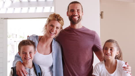 Portrait-Of-Smiling-Family-Standing-By-Open-Front-Door-In-Lounge-Of-New-Home
