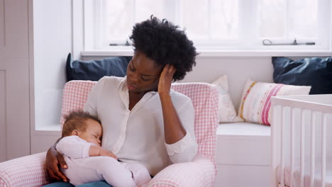 Anxious-New-Mother-Suffering-With-Post-Natal-Depression-Holding-Sleeping-Baby-Girl-In-Nursery-At-Home