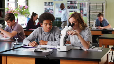 Gymnasiasten-Mit-Tutor-Unter-Verwendung-Des-Mikroskops-Im-Biologieunterricht
