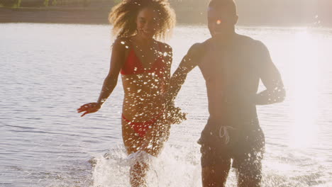 Young-mixed-race-couple-running-in-a-lake,-close-up