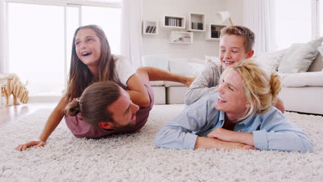 Portrait-Of-Children-Lying-On-Parents-Backs-On-Rug-In-Lounge-At-Home-Shot-In-Slow-Motion
