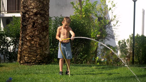 Boy-trying-to-cope-with-water-jet-when-watering-lawn