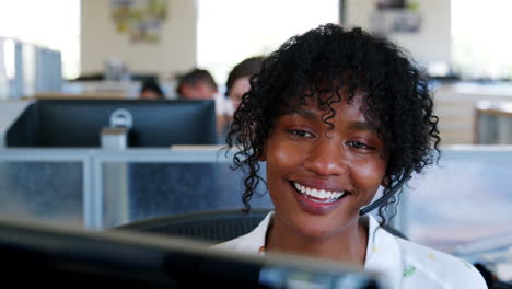 Young-black-woman-using-computer-in-a-call-centre,-close-up