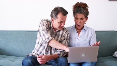 Älteres-Paar-Sitzt-Zu-Hause-Auf-Dem-Sofa-Und-Nutzt-Laptop-Computer,-Um-Online-Einzukaufen