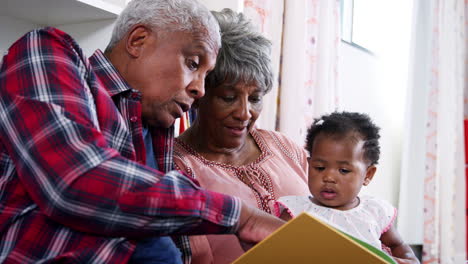Großeltern-Sitzen-Auf-Dem-Sofa-Und-Lesen-Ein-Buch-Mit-Ihrer-Kleinen-Enkelin-Zu-Hause