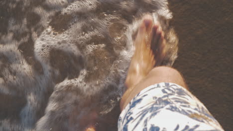 Vacationer-walking-along-the-sea-coast-and-waves-washing-his-feet