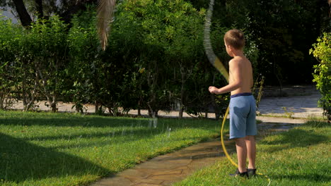 Child-having-fun-when-watering-lawn-with-hose