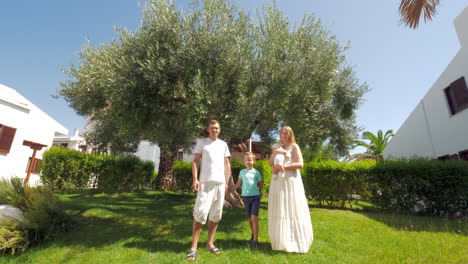 Junge-Familie-Mit-Zwei-Kindern-In-Der-Nähe-Eines-Olivenbaums-Im-Garten