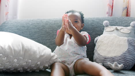 Baby-Girl-Sitting-On-Sofa-And-Clapping-At-Home