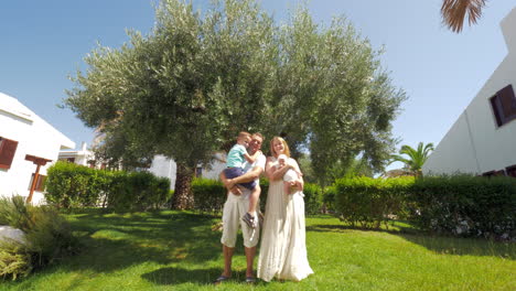 Parents-with-children-near-olive-tree-in-green-garden
