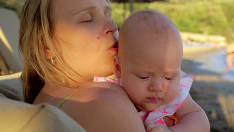 Loving-mother-kissing-baby-daughter-outdoor