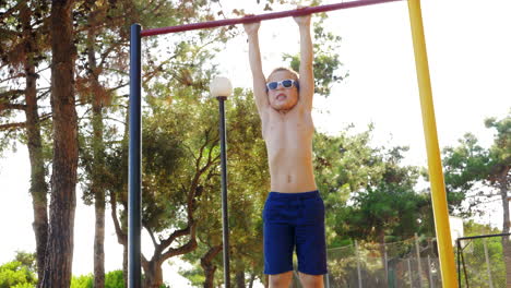 Boy-exercising-on-chin-up-bar-at-outdoor-sports-ground