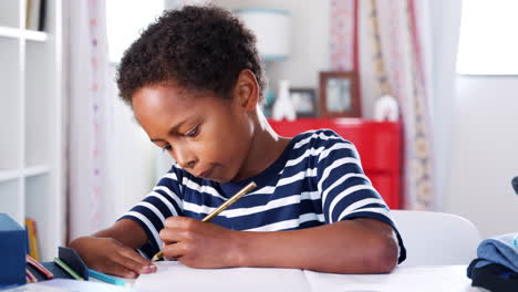 Young-Boy-Sitting-At-Desk-In-Bedroom-And-Drawing