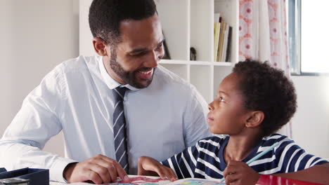 Father-Helps-Son-With-Homework-In-Bedroom-At-Home