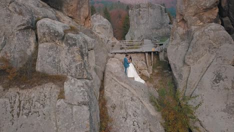 Newlyweds-stand-on-a-high-slope-of-the-mountain.-Groom-and-bride.-Arial-view