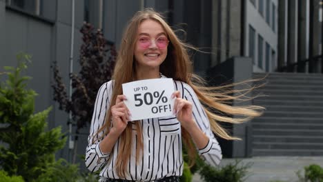 Teen-girl-showing-Up-To-50-percent-Off-inscription,-advertising-discounts,-shopping-on-Black-Friday