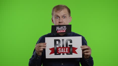 Man-shopper-holding-Black-Friday-Deals-advertisement-in-his-month-and-showing-Big-Sale-inscription