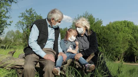 Grandparents-with-granddaughter-in-medical-masks-in-park.-Coronavirus-quarantine