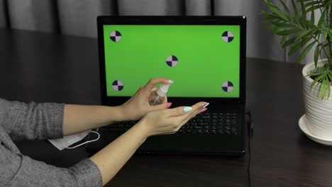Woman's-hands-use-sanitizer-near-laptop-with-green-screen.-Coronavirus