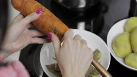 Female-housewife-hands-peeling-carrot-in-the-kitchen.