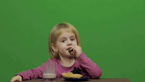 Mädchen-Sitzt-Am-Tisch-Und-Isst-Schokolade,-Kekse-Und-Trinkt-Kakao