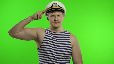 Young-sailor-man-salutes-with-hand-to-camera.-Seaman-guy-in-sailor's-vest