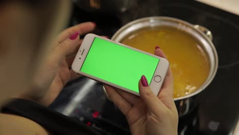Frau-Hält-Ein-Smartphone-Mit-Grünem-Bildschirm-Und-Kocht-Suppe