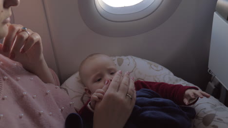 Mother-playing-with-baby-daughter-in-plane