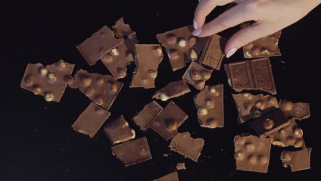 Woman-hand-takes-piece-of-chocolate-from-a-bunch-of-chocolate-pieces