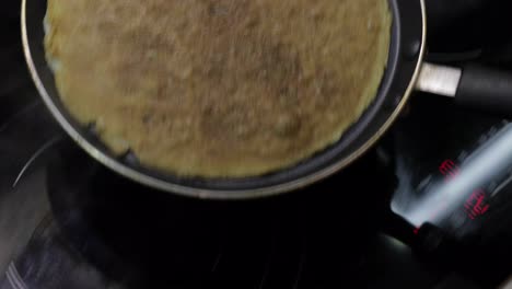 The-process-of-cooking-homemade-pancakes.-Woman-puts-pancake-from-pan-to-plate