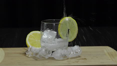 Pours-lemon-juice-into-glass-with-ice,-thyme-and-lemon-slices