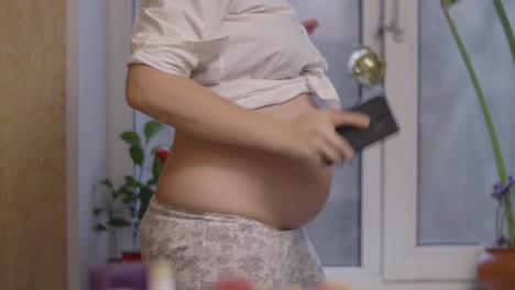 Pregnant-woman-being-happy-and-dancing-to-cellphone-music-at-home