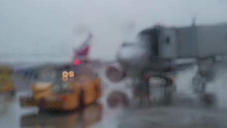 Tow-tractor-and-aircraft-view-on-rainy-day-through-the-terminal-window