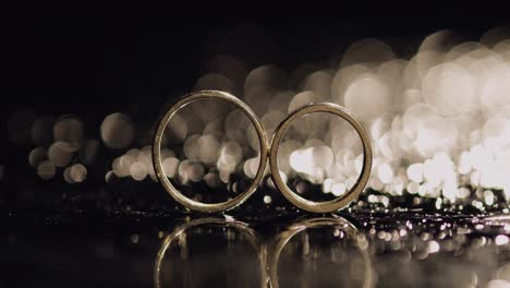 Wedding-rings-on-dark-water-surface-shining-with-light.-Close-up-macro