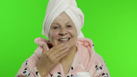 Elderly-grandmother-in-bathrobe.-Old-woman-applying-moisturizing-cream-on-face