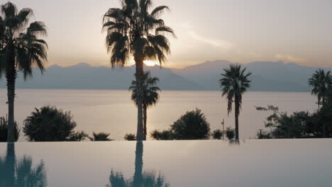 Sunset-scene-of-resort-with-swimming-pool-sea-and-mountains