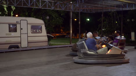 Adults-with-children-having-fun-driving-bumper-cars-at-fun-fair