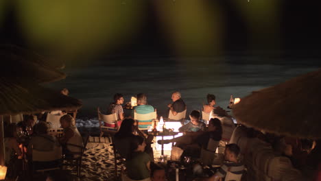 Beach-cafe-with-people-relaxing-and-having-drinks-by-the-sea-at-night