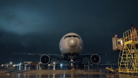 View-to-the-cockpit-and-engines-of-parked-airliner-in-airport-at-night