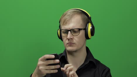 Guy-listens-to-music-in-wireless-yellow-headphones-and-dances.-Chroma-key