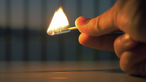 Hand-holding-burning-match-stick-in-the-dark