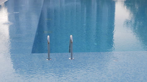 Eine-Wackelige-Oberfläche-Eines-Offenen-Schwimmbeckens-Mit-Einem-Glänzenden-Geländer