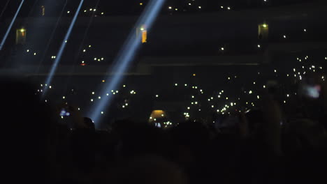 Crowded-concert-hall-music-fans-waving-lights-to-music