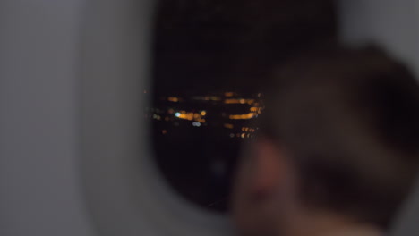 Kid-looking-at-night-city-from-flying-airplane
