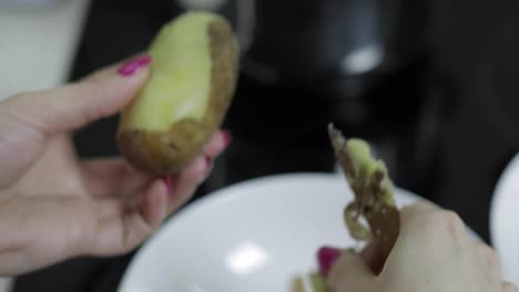 Female-housewife-hands-peeling-potatoes-in-the-kitchen.
