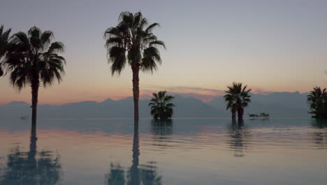 Scene-with-mountains-palms-and-swimming-pool-at-sunset-Turkey