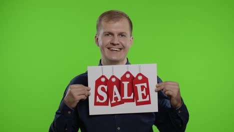 Great-discounts.-Happy-cheerful-blonde-man-in-blue-shirt-showing-Sale-word-advertisement-inscription
